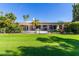 Spacious backyard with a covered patio, lush lawn, and a black iron fence at 24426 S Ribbonwood Dr, Sun Lakes, AZ 85248