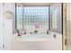 Relaxing bathroom with a large bathtub and a stylish glass block window at 24426 S Ribbonwood Dr, Sun Lakes, AZ 85248