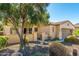 Tan stucco house with a brown garage door, mature tree, and desert landscaping at 27789 N 129Th Ln, Peoria, AZ 85383