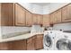 Laundry room with granite countertops, wood cabinets, and modern washer/dryer at 2166 E Caroline Ln, Tempe, AZ 85284