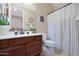 Clean bathroom with wood cabinets, shower/tub combo, and striped shower curtain at 19428 W Colter St, Litchfield Park, AZ 85340