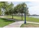 Curving concrete pathway winds through a grassy park with mature trees and lake views at 18610 W Porter Dr # 93, Goodyear, AZ 85338