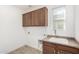 Laundry room with wood cabinets, granite countertop, and a utility sink at 15298 W Linden St, Goodyear, AZ 85338