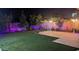 Landscaped backyard with artificial turf, lighting, and trees at 5526 S Grenoble St, Mesa, AZ 85212