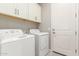 Bright laundry room, featuring washer, dryer, and upper cabinets at 43958 W Stonecreek Rd, Maricopa, AZ 85139