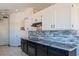 Modern kitchen with white cabinets, granite countertops, and a tile backsplash at 120 S Robins Ct, Chandler, AZ 85225