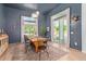 Bright dining room with a rustic wood table and black chairs, a large window and stylish light fixture at 3916 E Encanto St, Mesa, AZ 85205