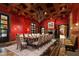 Formal dining room with red walls, wood ceiling beams, and marble floors at 8100 N 68Th St, Paradise Valley, AZ 85253