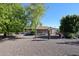 Backyard showcasing gravel, trees, and a view of the home's back elevation at 10220 W White Mountain Rd, Sun City, AZ 85351