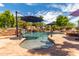 Inviting pool with waterfall feature, surrounded by a stone patio and umbrellas at 11305 S 195Th Dr, Buckeye, AZ 85326