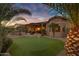 Backyard with putting green, palm trees, and a covered patio at sunset at 42597 W Kingfisher Dr, Maricopa, AZ 85138