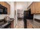 Galley kitchen with granite countertops, wood cabinets, and appliances at 1116 E Belmont Ave, Phoenix, AZ 85020