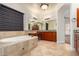 Bathroom boasts a large soaking tub and double vanity with wood cabinets at 2634 N 141St Ln, Goodyear, AZ 85395