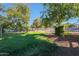 Green grassy backyard, partially fenced, with trees and dirt path at 4331 W Port Au Prince Ln, Glendale, AZ 85306