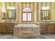 Elegant bathroom with double sinks, a large soaking tub, and yellow striped walls at 6440 E Odessa St, Mesa, AZ 85215