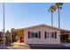 Front view of a tan manufactured home with maroon shutters and carport at 9302 E Broadway Rd # 9, Mesa, AZ 85208