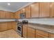 Kitchen with gas range, granite counters, and ample wood cabinetry at 44395 W Bailey Dr, Maricopa, AZ 85138