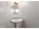 Powder room with pedestal sink and round mirror at 6705 W Orchid Ln, Peoria, AZ 85345