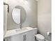 Modern powder room features white vanity, round mirror and toilet at 16944 W Coronado Rd, Goodyear, AZ 85395
