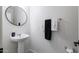 Clean bathroom with pedestal sink, round mirror, and dark towels at 4636 E Tierra Buena Ln, Phoenix, AZ 85032