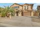 Two-story house with tan exterior, large garage, and palm trees in front at 16800 W Mesquite Dr, Goodyear, AZ 85338