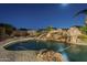 Night view of a kidney shaped pool and a rock waterfall feature at 24005 N 45Th Dr, Glendale, AZ 85310