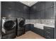 Modern laundry room with dark cabinetry, patterned backsplash, and farmhouse sink at 1480 E Raven Ct, Gilbert, AZ 85297