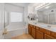Bathroom with double vanity, large mirror, and a bathtub at 16170 W Port Royale Ln, Surprise, AZ 85379