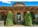 Inviting exterior entrance with stonework, arched metal door, and lush landscaping at 9533 E Rising Sun Dr, Scottsdale, AZ 85262