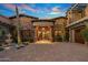 Elegant stone exterior with a courtyard entry and a three-car garage at 10612 E Winter Sun Dr, Scottsdale, AZ 85262