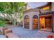 Courtyard entry with brick pavers, arched window, and wooden door at 13128 N 104Th Pl, Scottsdale, AZ 85260