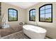 Spa-like bathroom with freestanding tub, large windows, and stone bench at 6717 E Solano Dr, Paradise Valley, AZ 85253