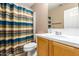 Clean bathroom with striped shower curtain and wood vanity at 44043 W Cypress Ln, Maricopa, AZ 85138