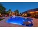 Night view of a sparkling pool with surrounding patio and lights at 7801 E Davenport Dr, Scottsdale, AZ 85260