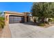 Front view of a tan house with a dark-colored garage door and driveway at 856 E Harmony Way, San Tan Valley, AZ 85140