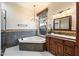 Elegant bathroom with corner bathtub, dark tile, and wood vanity at 4256 N Desert Oasis Cir, Mesa, AZ 85207