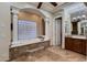 Spa-like bathroom with a luxurious soaking tub and glass block window at 18135 W Missouri Ave, Litchfield Park, AZ 85340