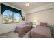 Bedroom with two twin beds, window seat, and view of palm trees at 18483 N Deer Grass Ct, Surprise, AZ 85374