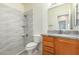 Bathroom with wood cabinets, granite countertop, and wave patterned shower tile at 25575 W Lynne Ln, Buckeye, AZ 85326