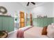 Bedroom with double doors to bathroom, soft pink bedding, and green wall paneling at 2346 E Sanoque Ct, Gilbert, AZ 85298
