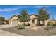 Tan three-car garage stucco home with mature trees and desert landscaping at 27046 W Yukon Dr, Buckeye, AZ 85396