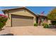 Tan colored home with a two-car garage and drought-tolerant landscaping at 19606 W Grant St, Buckeye, AZ 85326