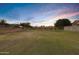 Peaceful backyard view with pond and neighborhood homes at sunset at 20566 N Lemon Drop Dr, Maricopa, AZ 85138