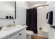 Clean bathroom with a white vanity, black shower curtain, and bathtub at 5203 W Roundhouse Rd, Laveen, AZ 85339