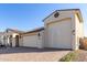 Tan two-story house with a three-car garage and desert landscaping at 5203 W Roundhouse Rd, Laveen, AZ 85339