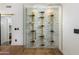 Modern glass-enclosed wine cellar with gold metal racking at 8701 E Highland Ave, Scottsdale, AZ 85251