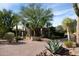 Desert landscape with a brick driveway, mature trees, and a modern entryway at 10040 E Happy Valley Rd # 504, Scottsdale, AZ 85255