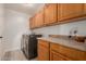 Laundry room with washer, dryer, and ample wood cabinets at 25714 N 70Th Ln, Peoria, AZ 85383
