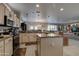 Open kitchen with island, stainless steel appliances, and view into the living room at 16316 W Willow Creek Ln, Surprise, AZ 85374