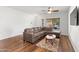 Living room with L-shaped sofa, hardwood floors, coffee table, and ceiling fan at 44032 W Garden Ln, Maricopa, AZ 85139